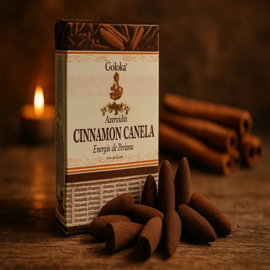 Incenso em cones de canela Goloka sobre superfície de madeira, com vela acesa e pau de canela ao fundo, representando energia e concentração.